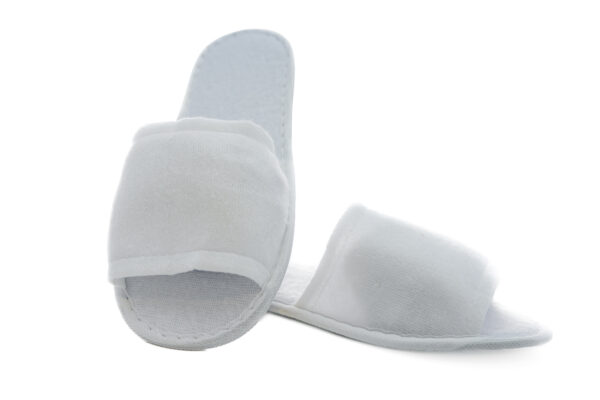 White open-toe hotel slippers on a soft background